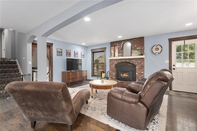 living room with dark wood-type flooring and a brick fireplace