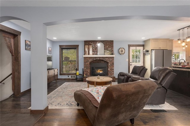 living room featuring a fireplace, dark wood-type flooring, and sink