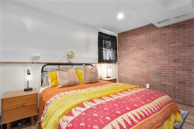 bedroom featuring wood-type flooring and brick wall