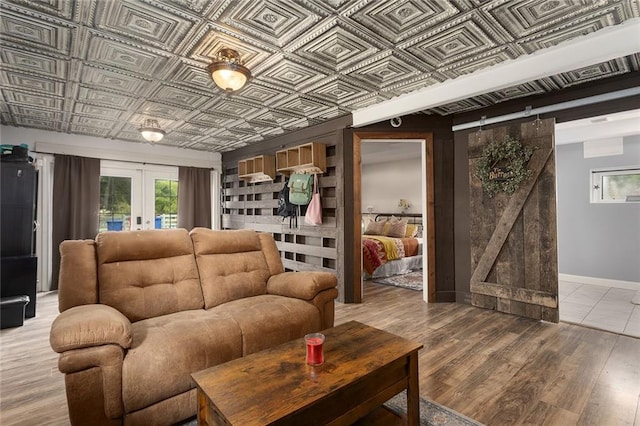 living room featuring light wood-type flooring, french doors, and a barn door