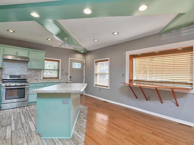 kitchen with tasteful backsplash, gas range, a wealth of natural light, and a center island