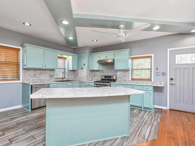 kitchen featuring sink, a center island, appliances with stainless steel finishes, ceiling fan, and decorative backsplash