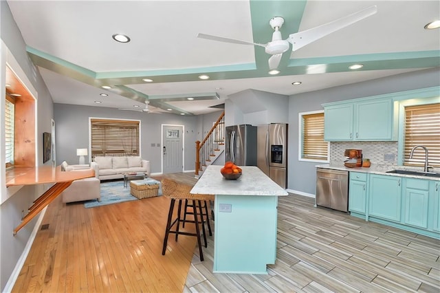 kitchen with sink, a breakfast bar, stainless steel appliances, tasteful backsplash, and a kitchen island