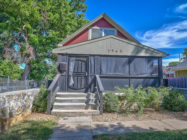 view of front of property featuring a sunroom and fence