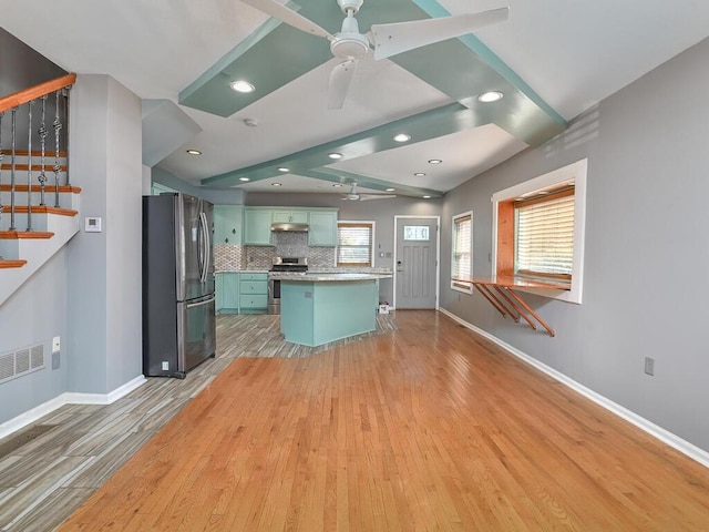 kitchen with appliances with stainless steel finishes, a breakfast bar, decorative backsplash, a center island, and green cabinets