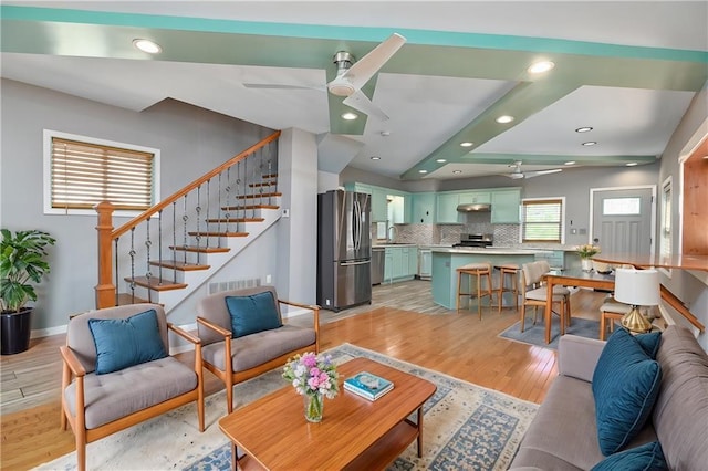 living room featuring ceiling fan, sink, and light hardwood / wood-style floors