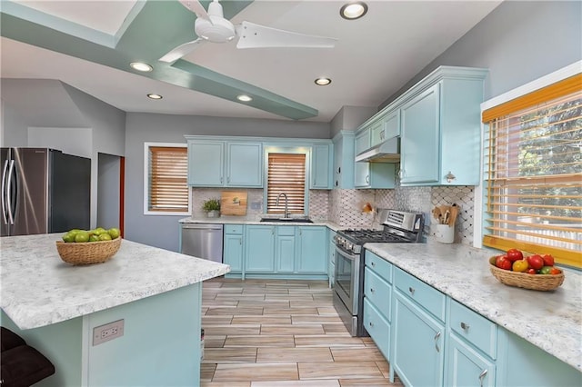 kitchen featuring tasteful backsplash, sink, blue cabinetry, and appliances with stainless steel finishes