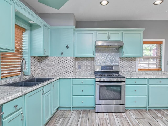 kitchen featuring gas range, light stone countertops, sink, and decorative backsplash