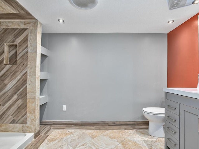 bathroom with walk in shower, vanity, and toilet