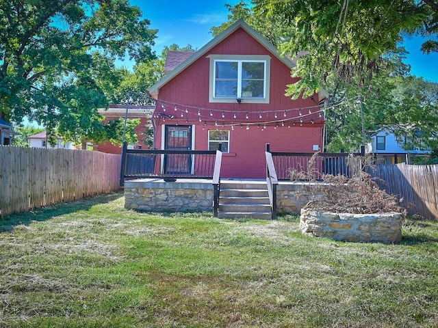 back of property featuring a wooden deck and a lawn