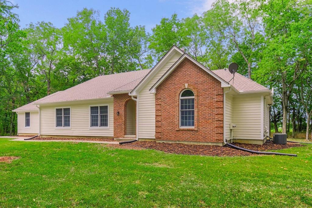 view of front of home with central AC and a front lawn