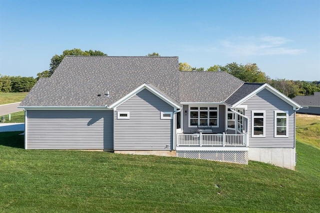 back of house with a shingled roof and a lawn