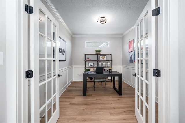 home office featuring light wood-style flooring, ornamental molding, a textured ceiling, and french doors