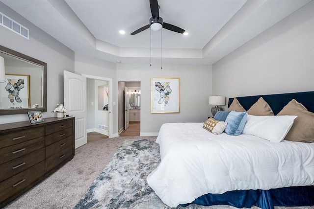 bedroom featuring visible vents, baseboards, connected bathroom, a tray ceiling, and recessed lighting