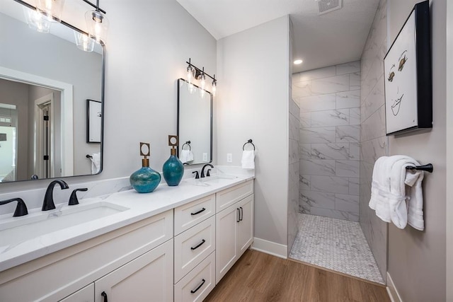 full bath featuring double vanity, wood finished floors, walk in shower, and a sink