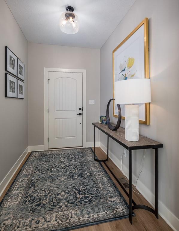 entryway with baseboards and wood finished floors