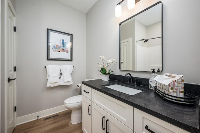 full bathroom with visible vents, toilet, vanity, wood finished floors, and baseboards