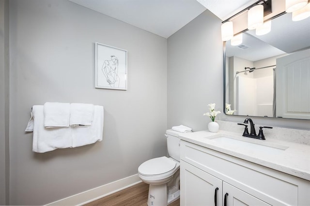 bathroom with baseboards, toilet, wood finished floors, walk in shower, and vanity