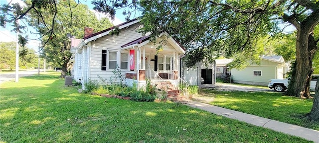 bungalow-style house with a front yard, covered porch, and central air condition unit