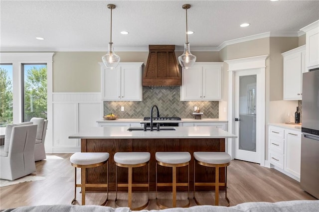 kitchen with ornamental molding, stainless steel fridge, premium range hood, and light hardwood / wood-style floors