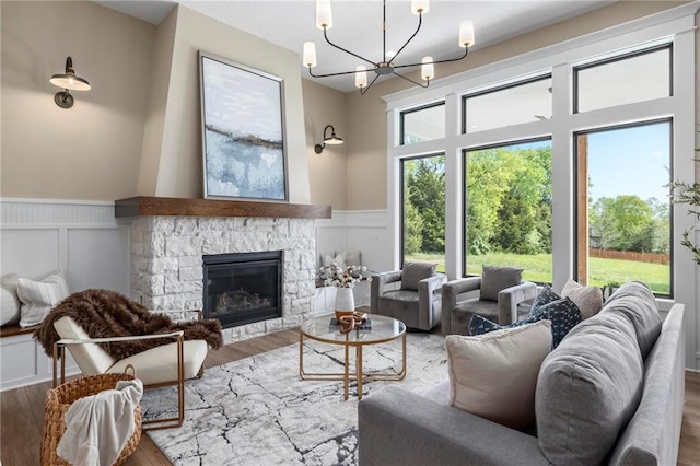 living room with a fireplace, a towering ceiling, wood-type flooring, and an inviting chandelier