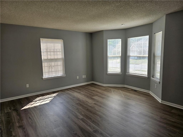 spare room with dark wood-style flooring, a textured ceiling, and baseboards