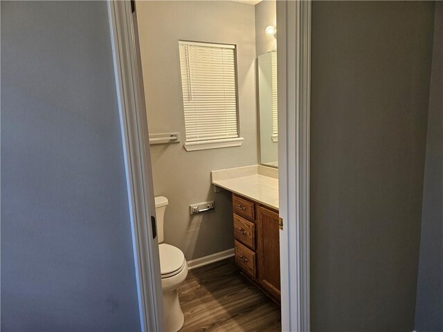 bathroom with baseboards, vanity, toilet, and wood finished floors