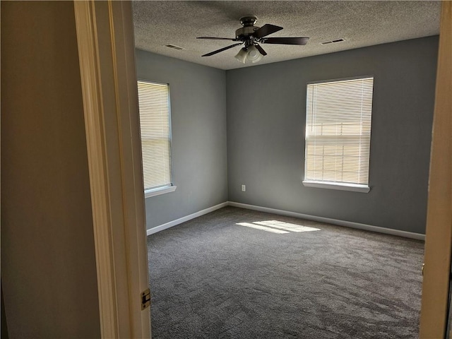 carpeted spare room with baseboards, visible vents, and a ceiling fan