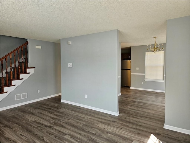 unfurnished room featuring dark wood-style floors, stairs, visible vents, and an inviting chandelier