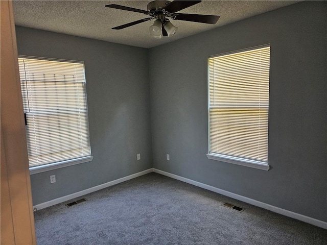 empty room with baseboards, carpet, visible vents, and a textured ceiling