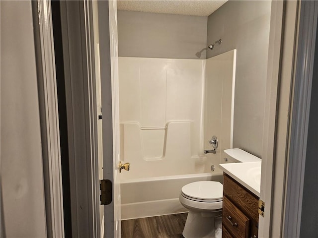 full bathroom featuring toilet, wood finished floors,  shower combination, a textured ceiling, and vanity