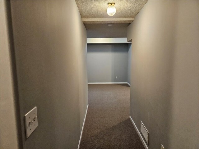 hall with carpet floors, visible vents, a textured ceiling, and baseboards