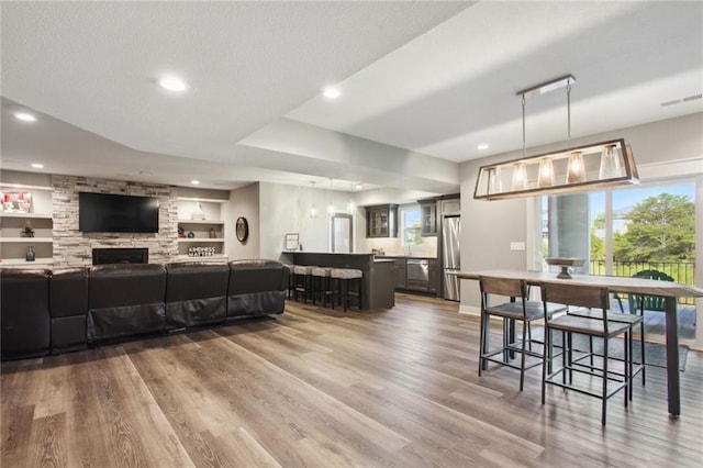 dining room featuring a wealth of natural light, hardwood / wood-style floors, built in shelves, and a fireplace