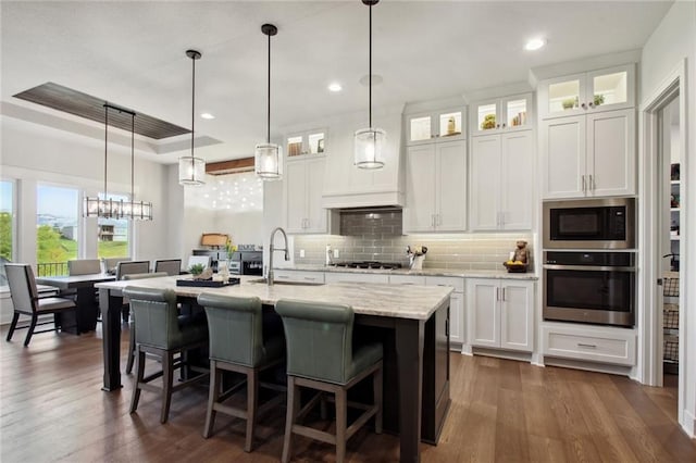 kitchen with dark hardwood / wood-style flooring, stainless steel appliances, decorative light fixtures, and white cabinets