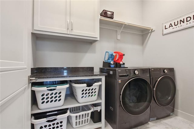 clothes washing area featuring cabinets and washer and clothes dryer