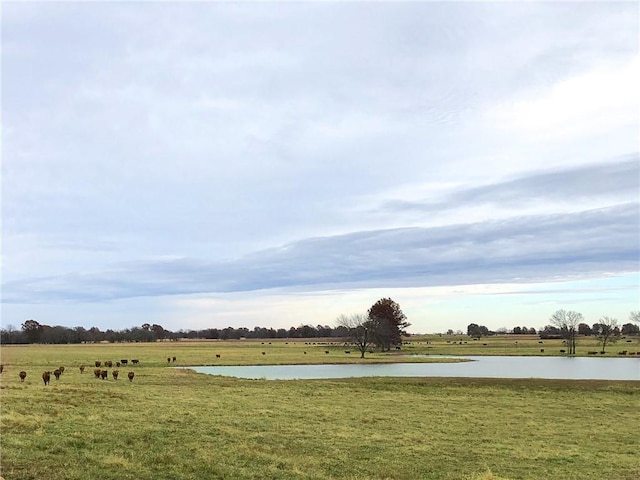 surrounding community featuring a water view, a lawn, and a rural view