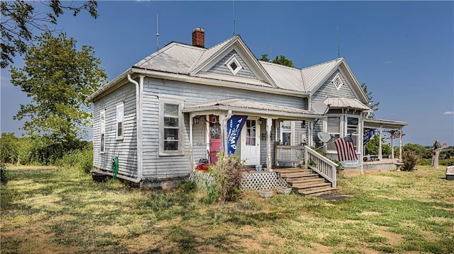 view of front of house with a porch, a front yard, and a chimney