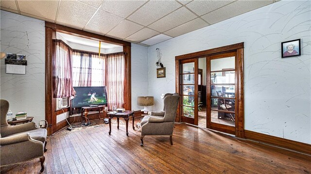 sitting room featuring french doors, wood-type flooring, and a paneled ceiling