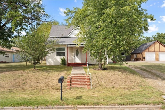 view of property hidden behind natural elements featuring an outdoor structure, a garage, and a front yard