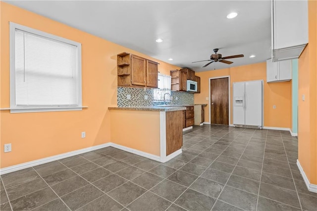 kitchen featuring ceiling fan, dark tile patterned flooring, white appliances, and decorative backsplash