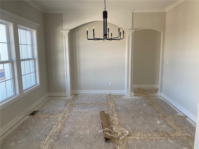 unfurnished dining area featuring ornate columns, crown molding, and a notable chandelier