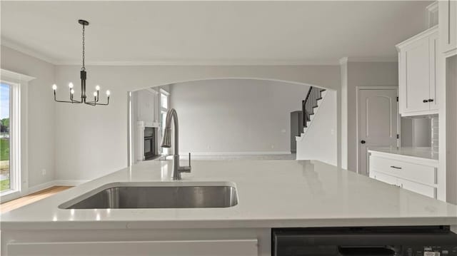 kitchen with sink, light stone counters, decorative light fixtures, a notable chandelier, and white cabinets