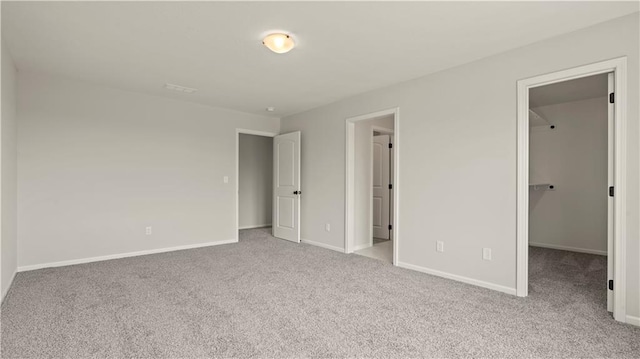 unfurnished bedroom featuring a walk in closet and light carpet