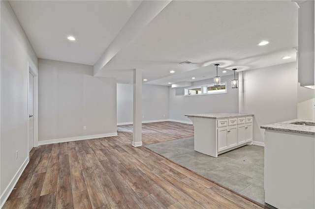 below grade area featuring visible vents, baseboards, light wood-style flooring, a sink, and recessed lighting