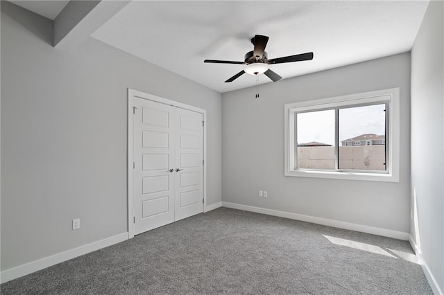 unfurnished bedroom featuring a ceiling fan, a closet, baseboards, and carpet flooring