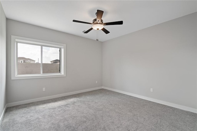 carpeted spare room with baseboards and a ceiling fan