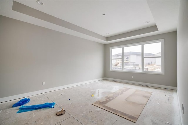 unfurnished room featuring a tray ceiling and baseboards