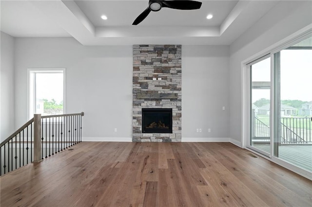 unfurnished living room with a raised ceiling, a fireplace, baseboards, and wood finished floors