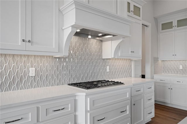 kitchen featuring tasteful backsplash, custom range hood, stainless steel gas cooktop, and white cabinetry