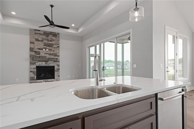 kitchen with open floor plan, a raised ceiling, ceiling fan, and a sink